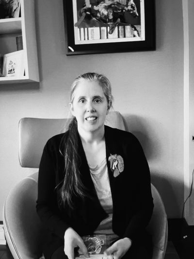 Woman with long hair sitting in a chair, smiling.