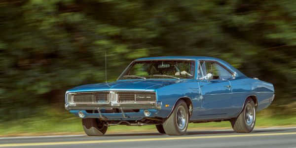 Blue classic muscle car driving on a road.