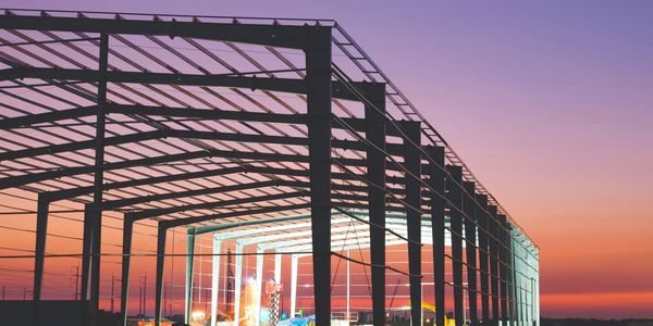 Steel framework of a building under construction at sunset.