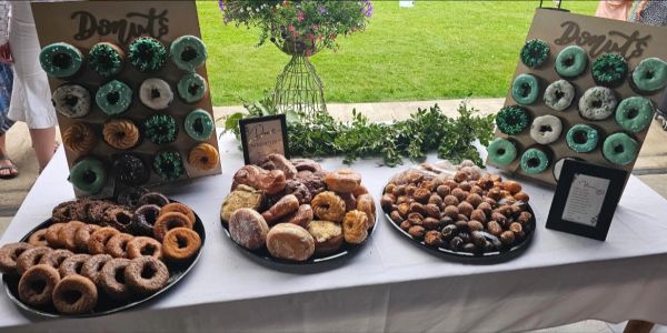 Table with various types of donuts on trays and stands.