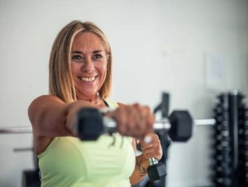 A woman lifting dumbbells and smiling.
