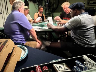 Five men playing poker around a table with chips and cards.