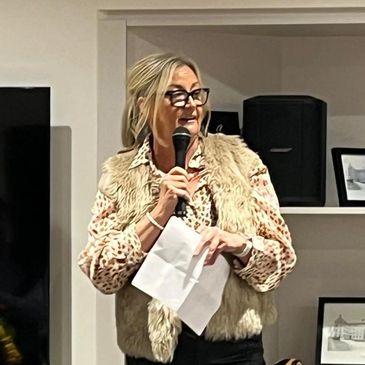 Woman speaking into microphone holding papers indoors.