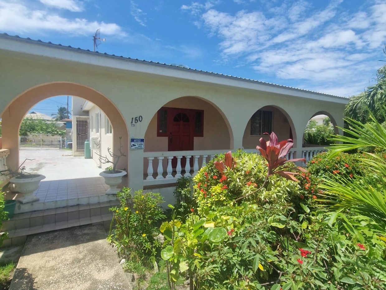 A house with arches and a garden full of green plants and flowers.