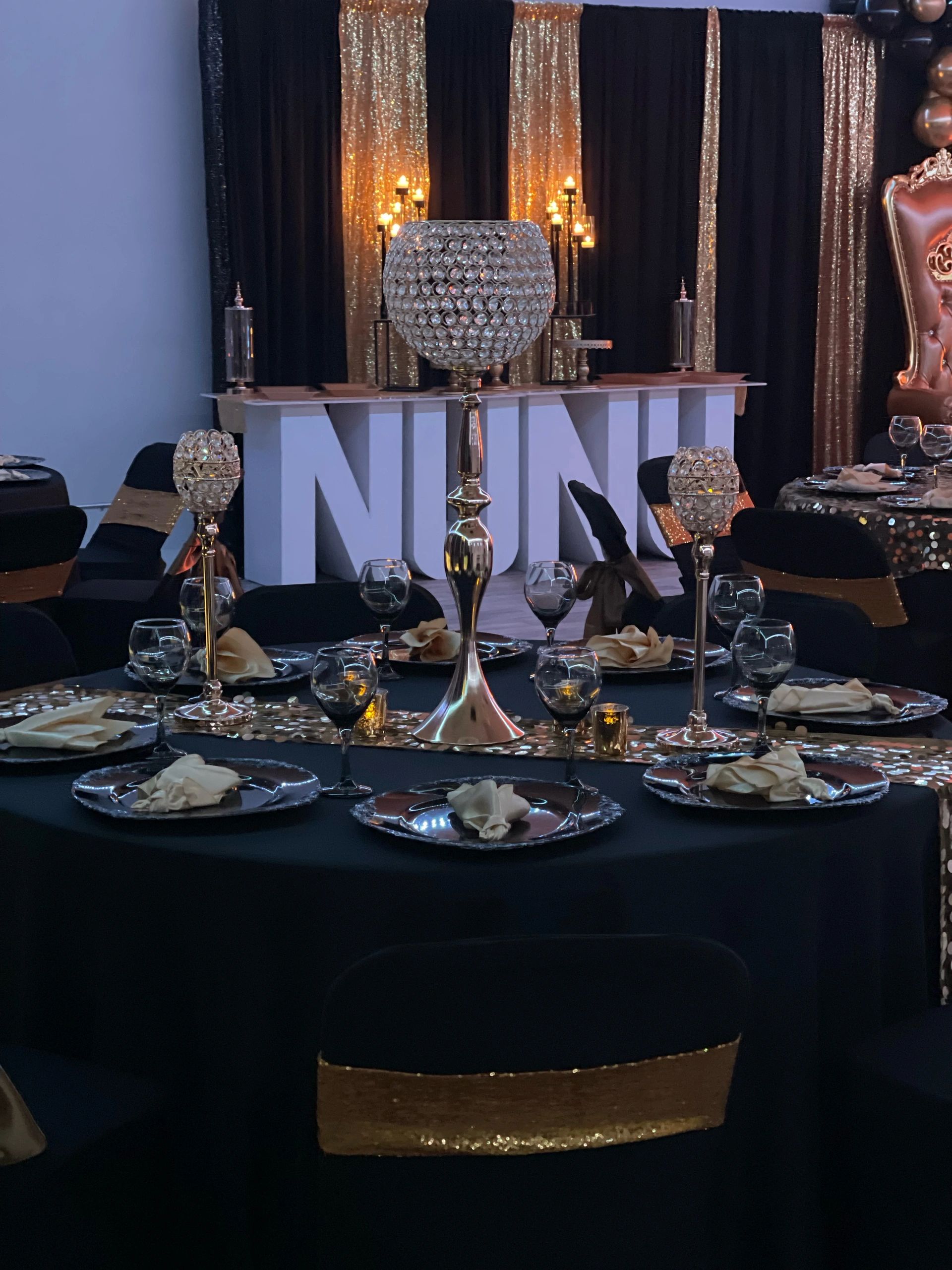 Elegant black and gold themed event setup with crystal candle holders and luxurious table settings.
