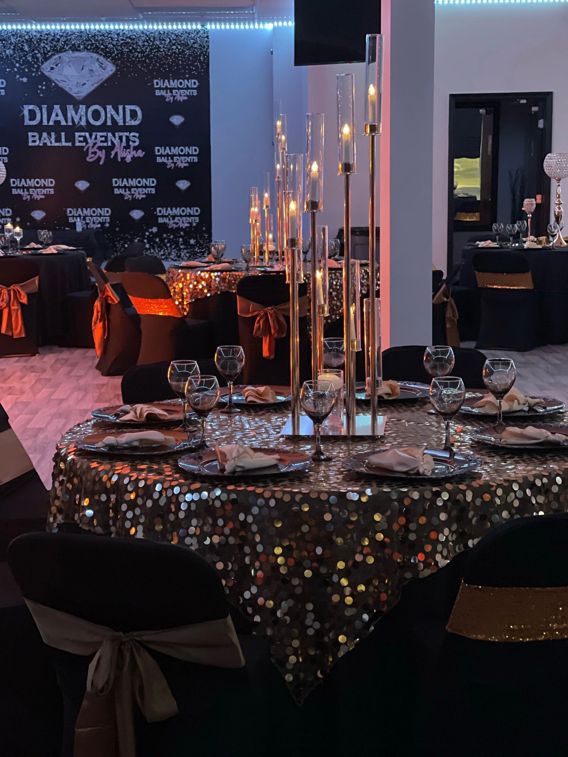 Elegant event setup with sparkling tablecloths and candlelit centerpieces.