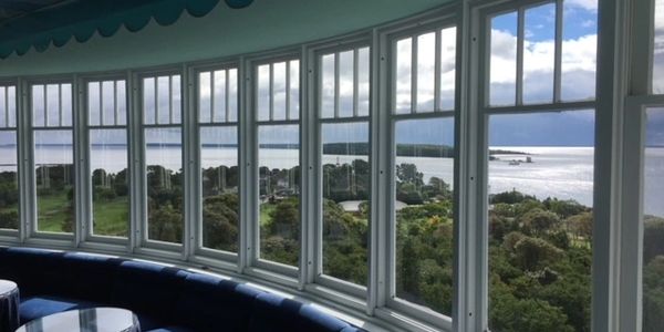 Curved seating with large windows overlooking a lush landscape and water.