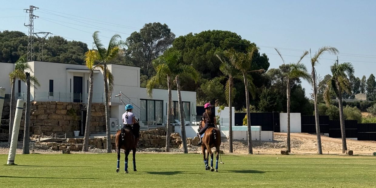Dos personas montando caballos en un campo verde.