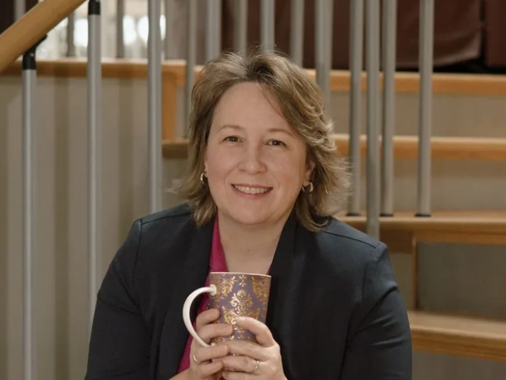 Smiling woman holding a decorative mug.