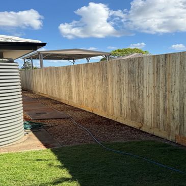 New wooden fence along a backyard with a water tank.