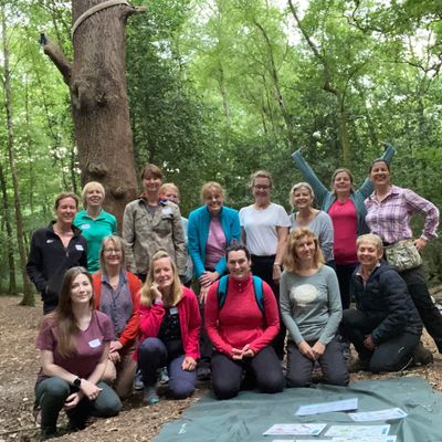 Group engaging in a hands-on bushcraft activity in a serene Surrey woodland.