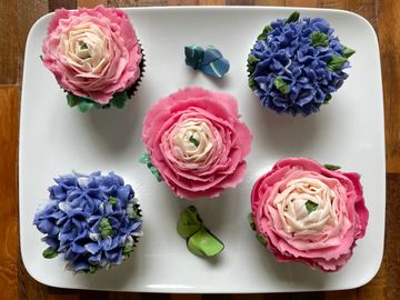 A stunning display of blue hydrangeas and ranunculus flowers in a vibrant pink 