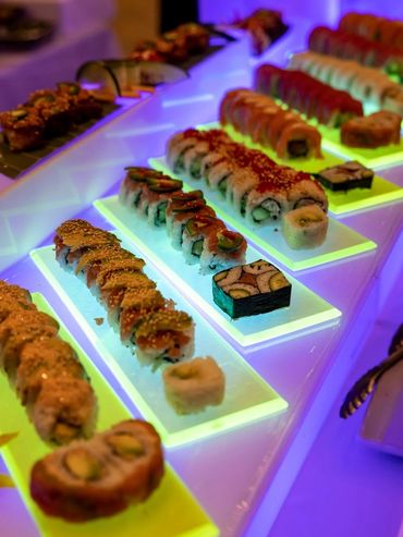 Assorted sushi rolls displayed on illuminated trays at a restaurant.