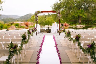 Outdoor wedding setup with floral decorations and white chairs.