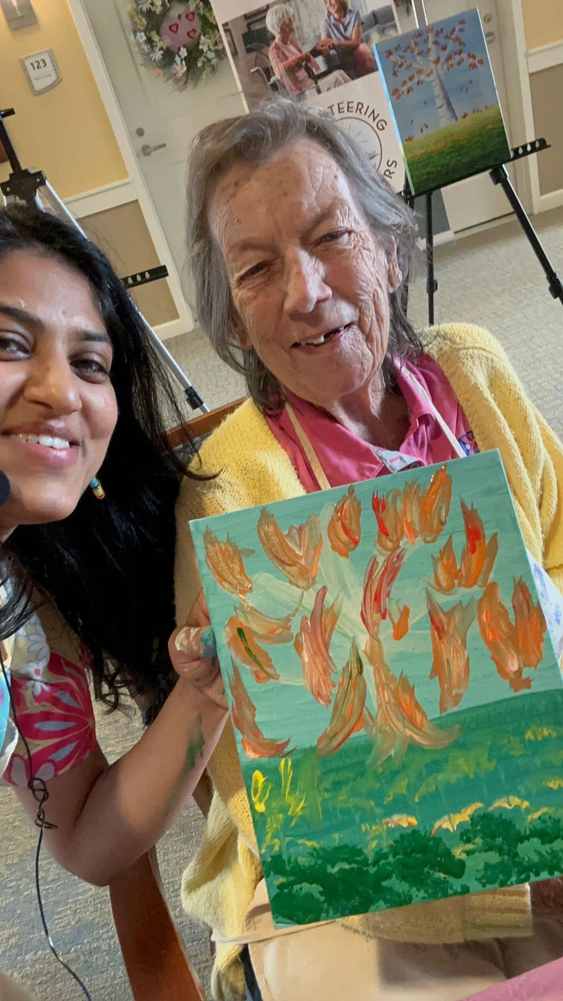 Workshop participant holding artwork next to teacher.
