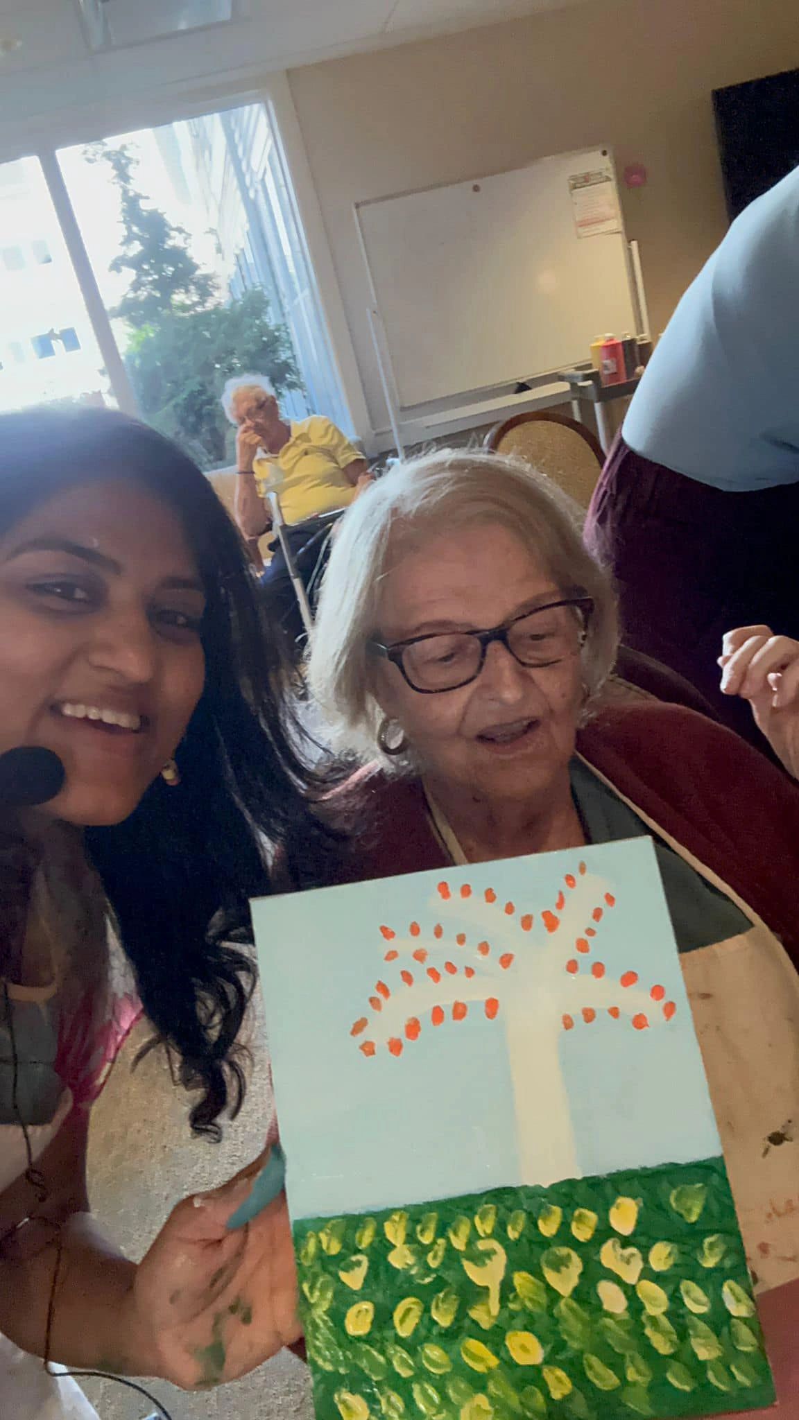 Workshop participant holding artwork next to teacher.