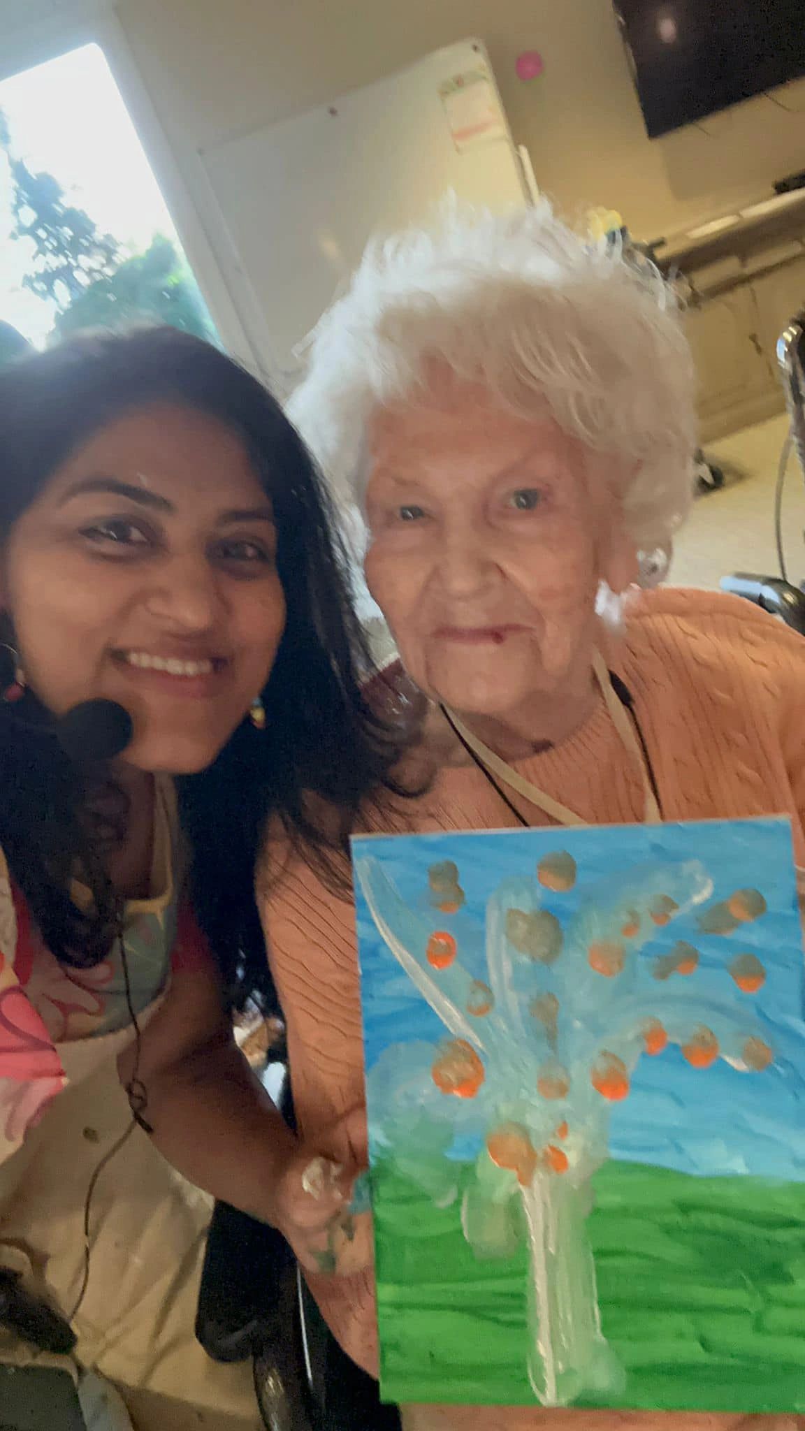 Workshop participant holding artwork next to teacher.