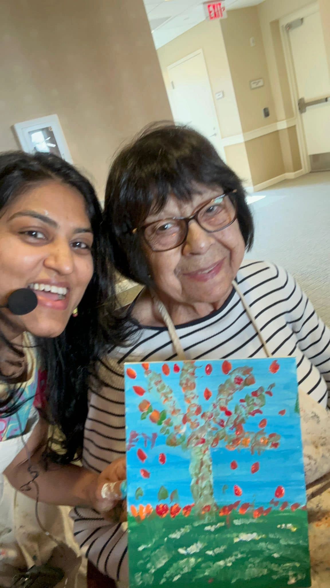 Workshop participant holding artwork next to teacher.