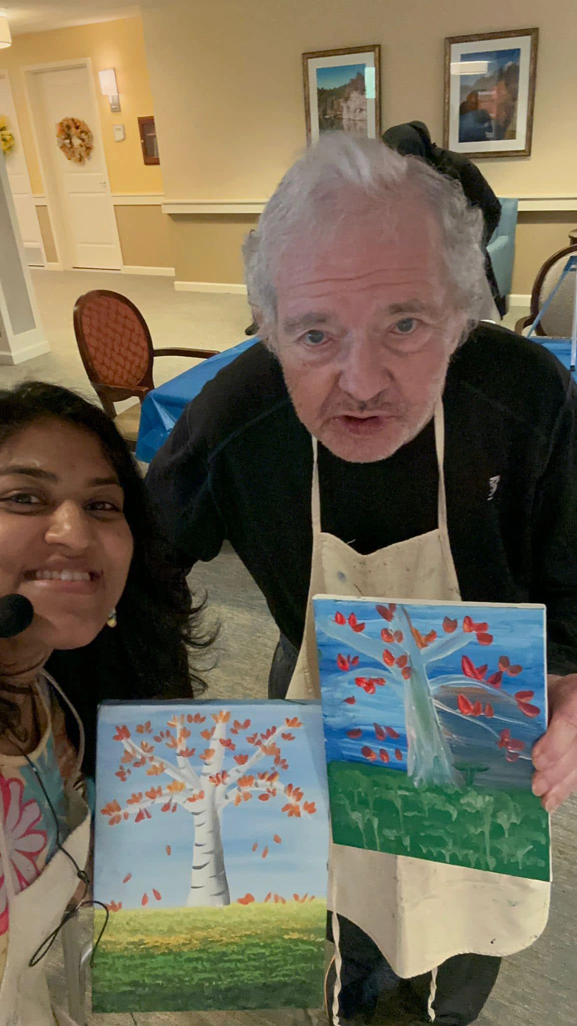 Workshop participant holding artwork next to teacher.