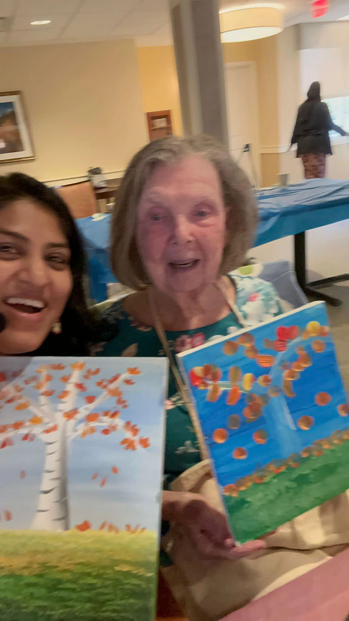 Workshop participant holding artwork next to teacher.