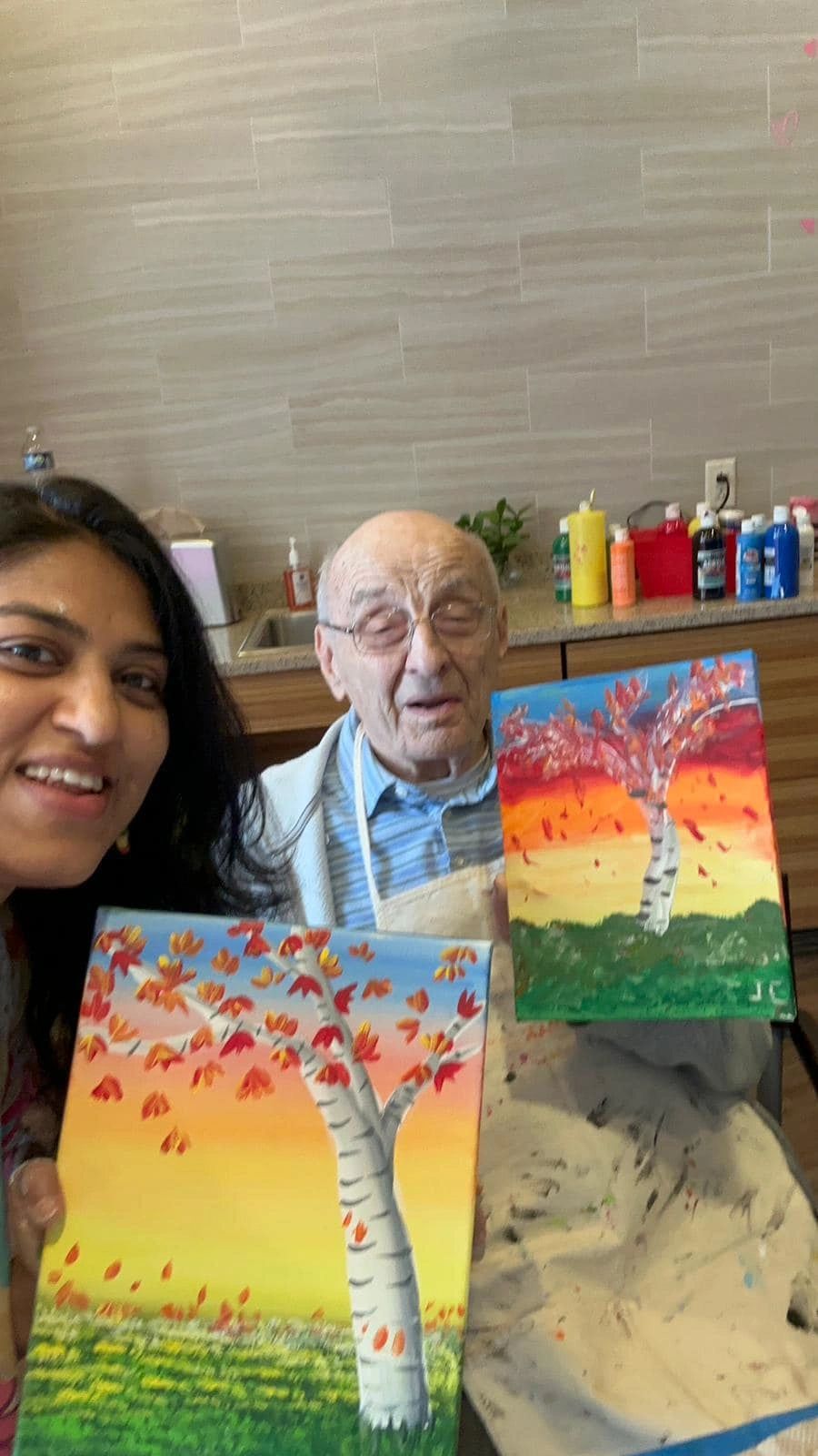 Workshop participant holding artwork next to teacher.