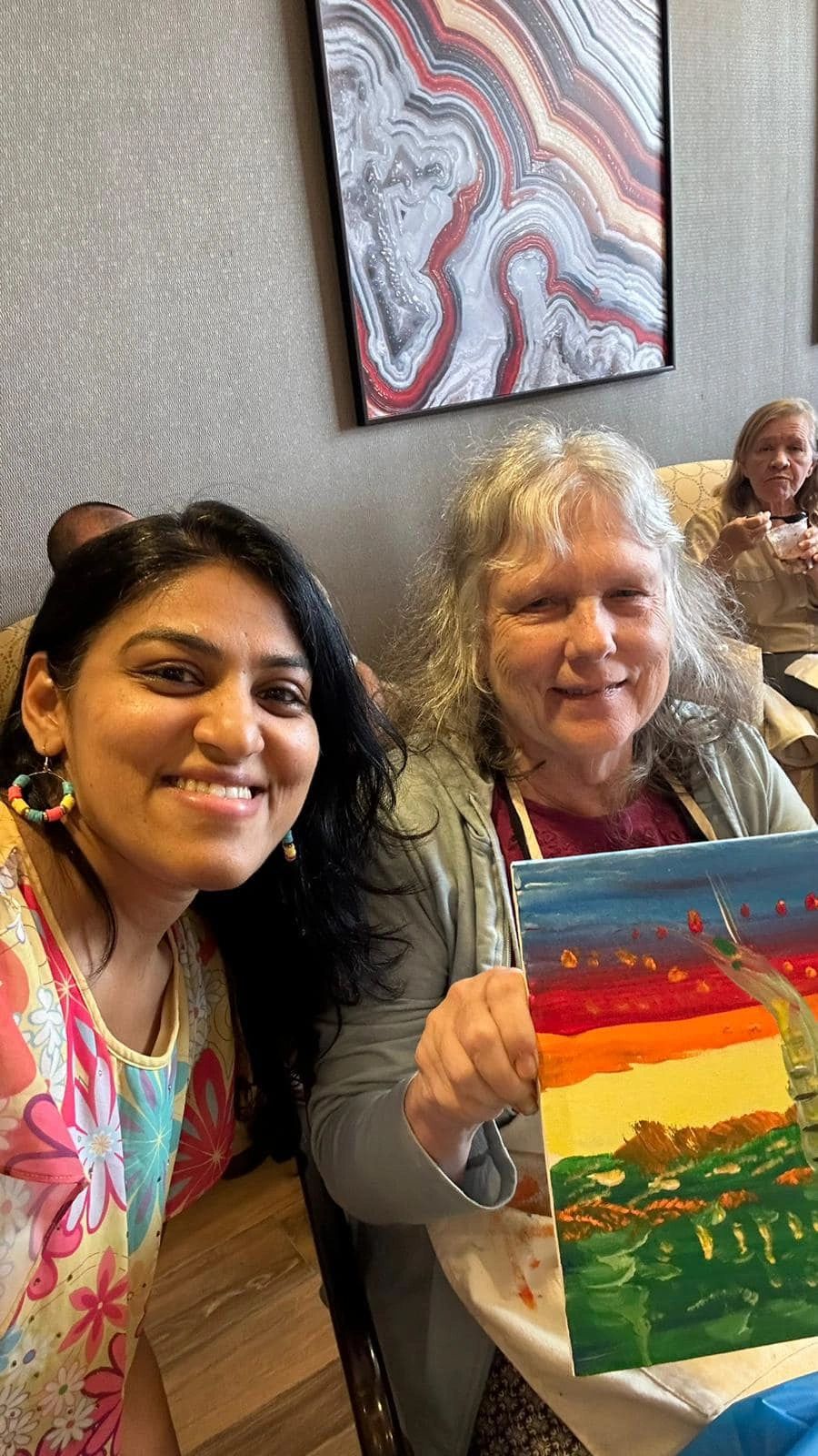 Workshop participant holding artwork next to teacher.