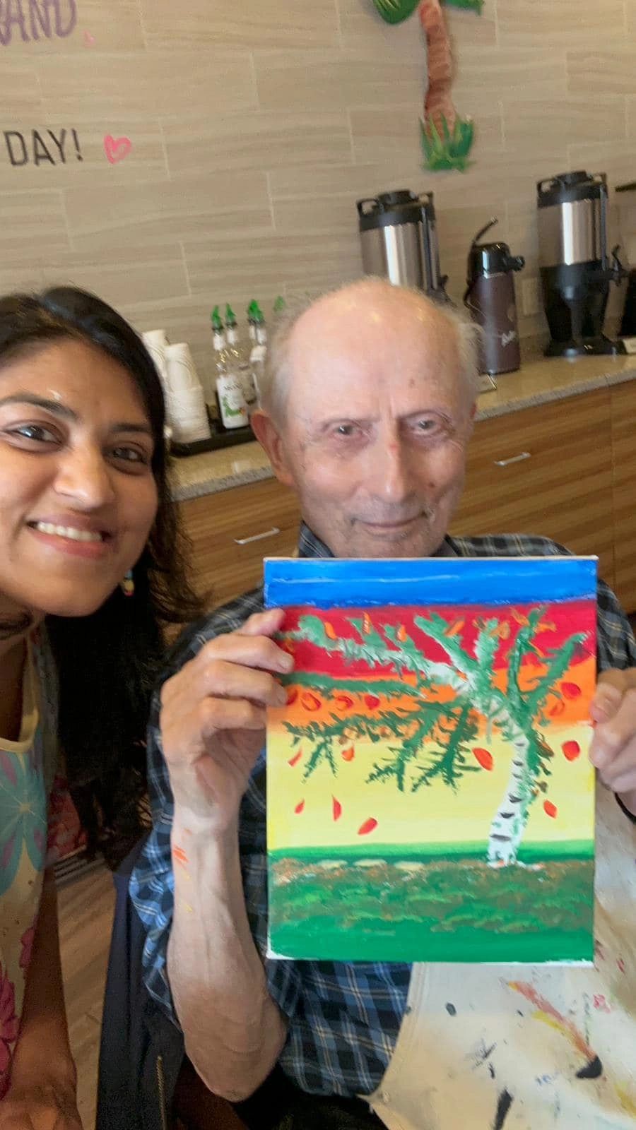 Workshop participant holding artwork next to teacher.