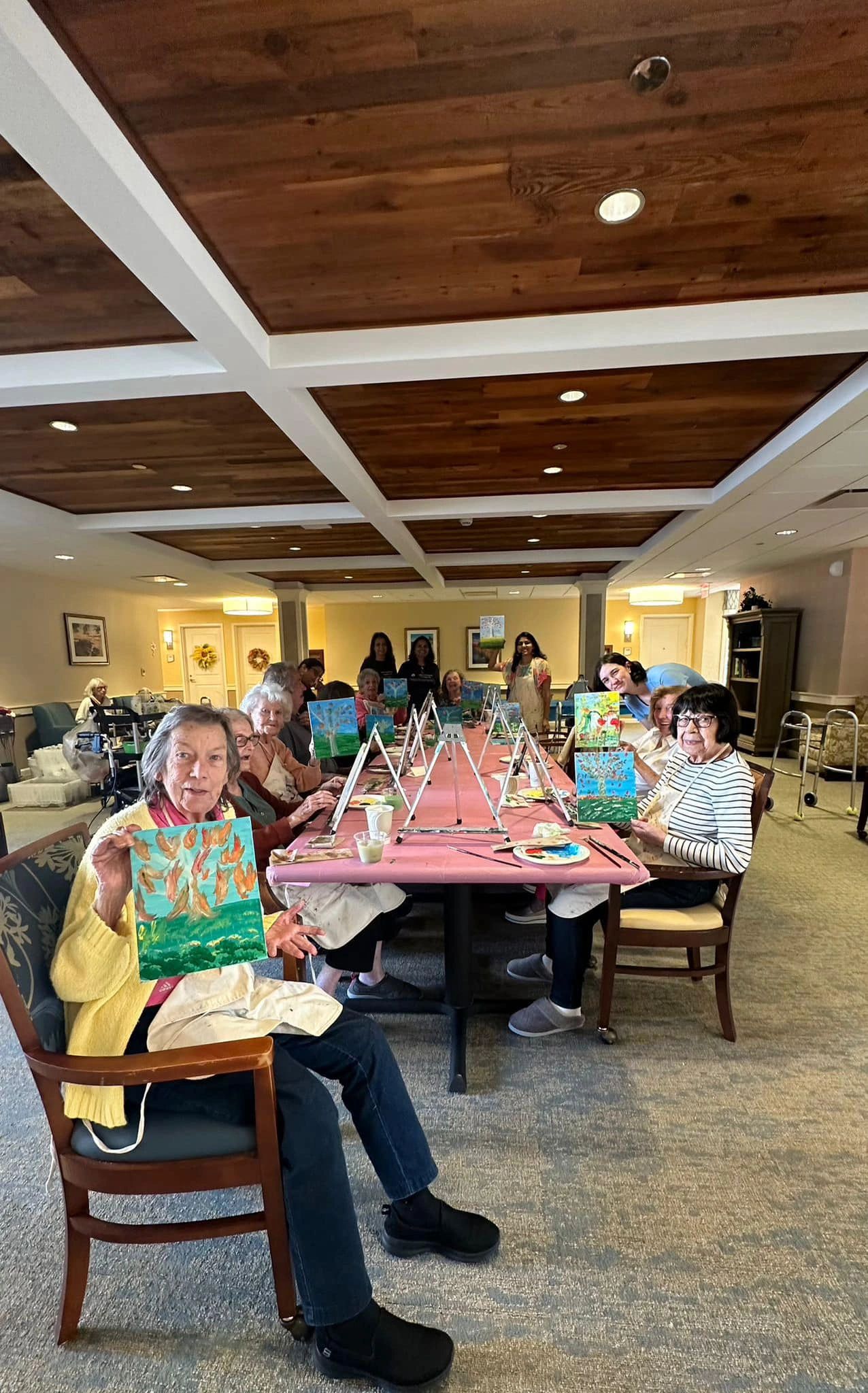 Workshop table with participants holding their artwork.