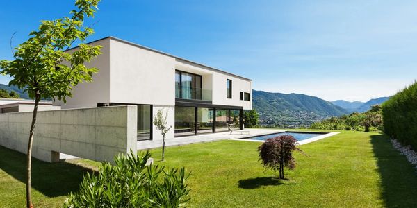 Modern house with a pool and mountain view on a sunny day.