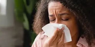 lady sneezing into a tissue due to allergies, pollen or hayfever