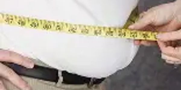 man with excess weight or fat around his abdomen being measured