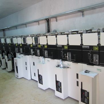 Row of industrial electrical switchgear units in a utility room.