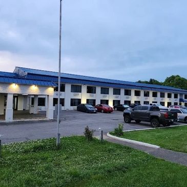 Exterior of a motel with parked cars at dusk.