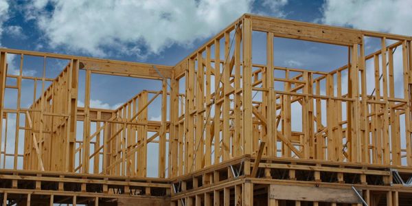 Wooden frame structure of a house under construction against a cloudy sky.
