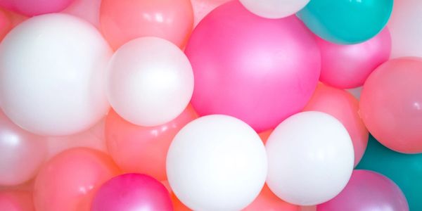 Colorful peach, pink, white, and turquoise party balloon wall.