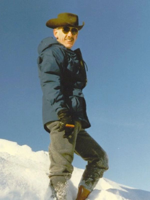 Man in a cowboy hat standing on snow.