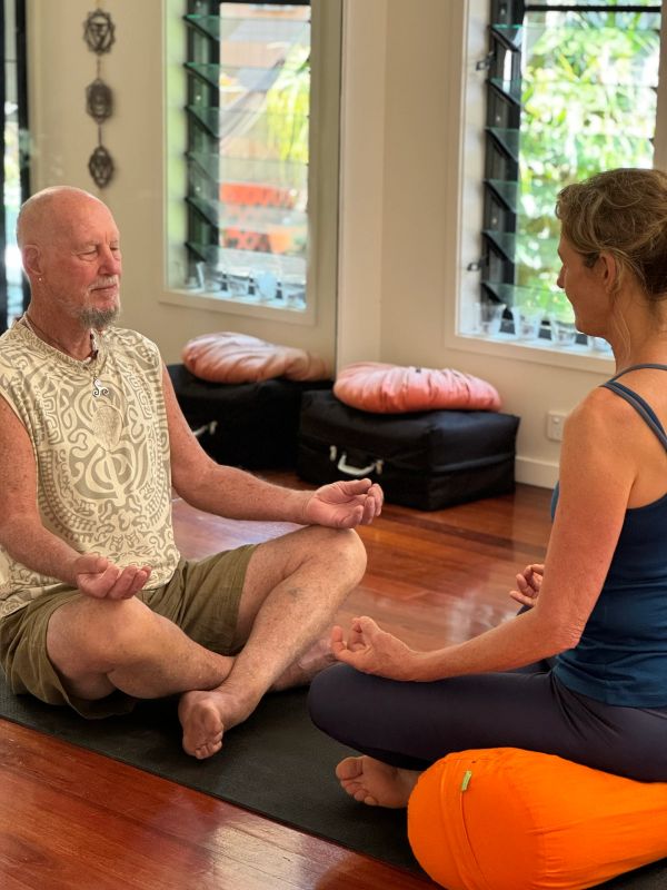 Two people meditating indoors on mats.