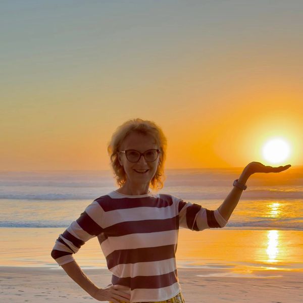 Woman holding the sun at sunset on the beach.