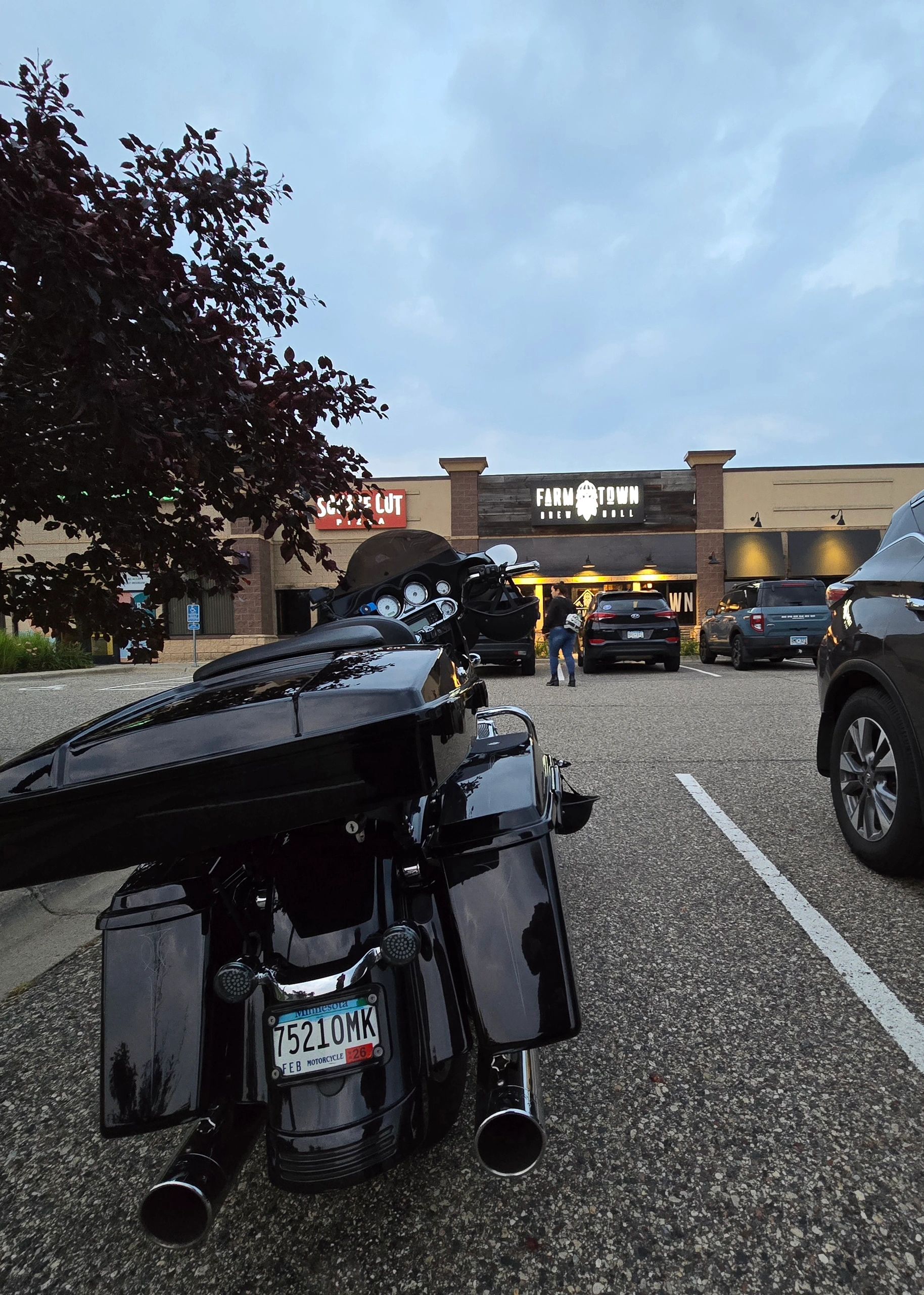 Black motorcycle parked in front of restaurants during evening.