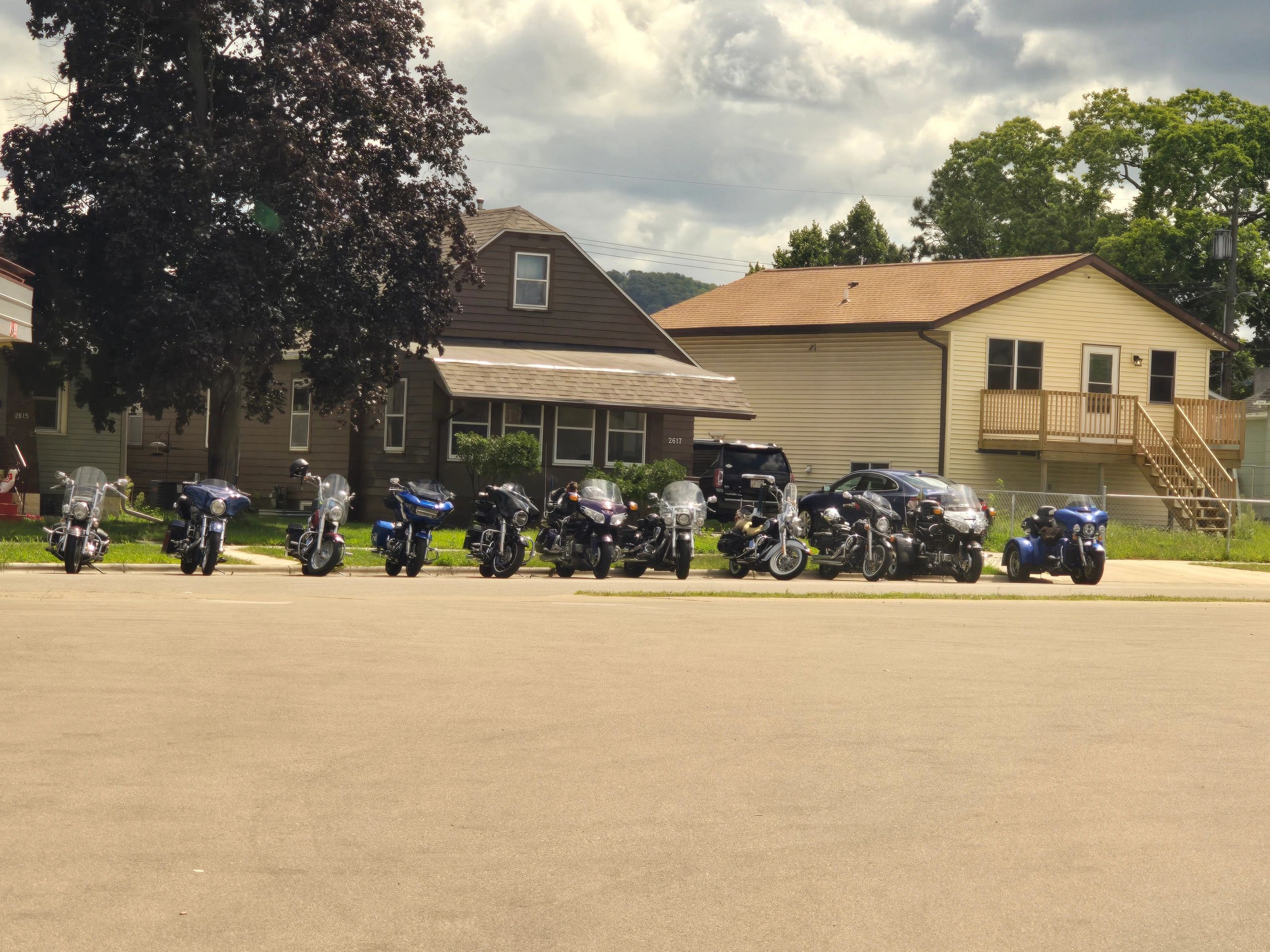 A row of motorcycles parked in front of houses on a cloudy day.