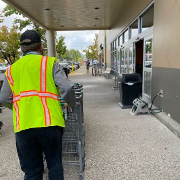 A man in a safety vest pushing a shopping cart