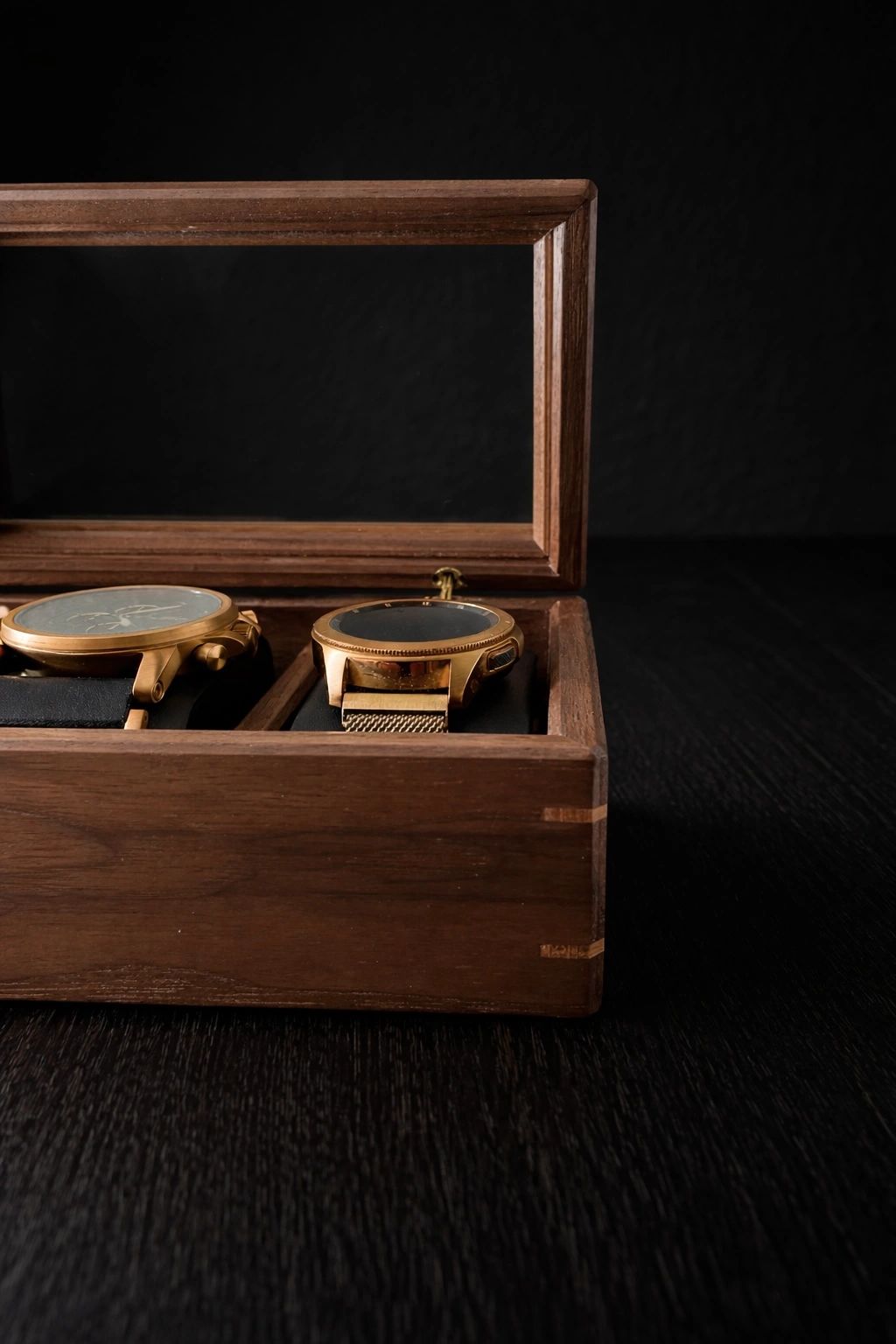 Two gold watches in a wooden box.