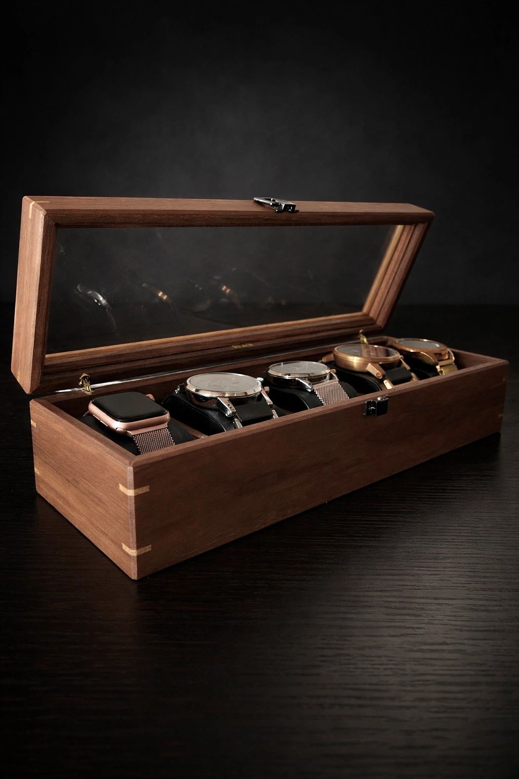Wooden box displaying five watches with clear lid.