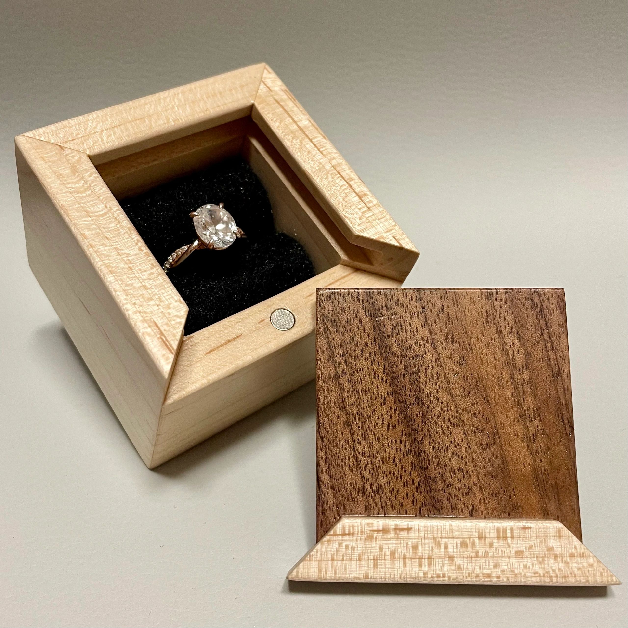 Engagement ring in a wooden box with a removable lid.