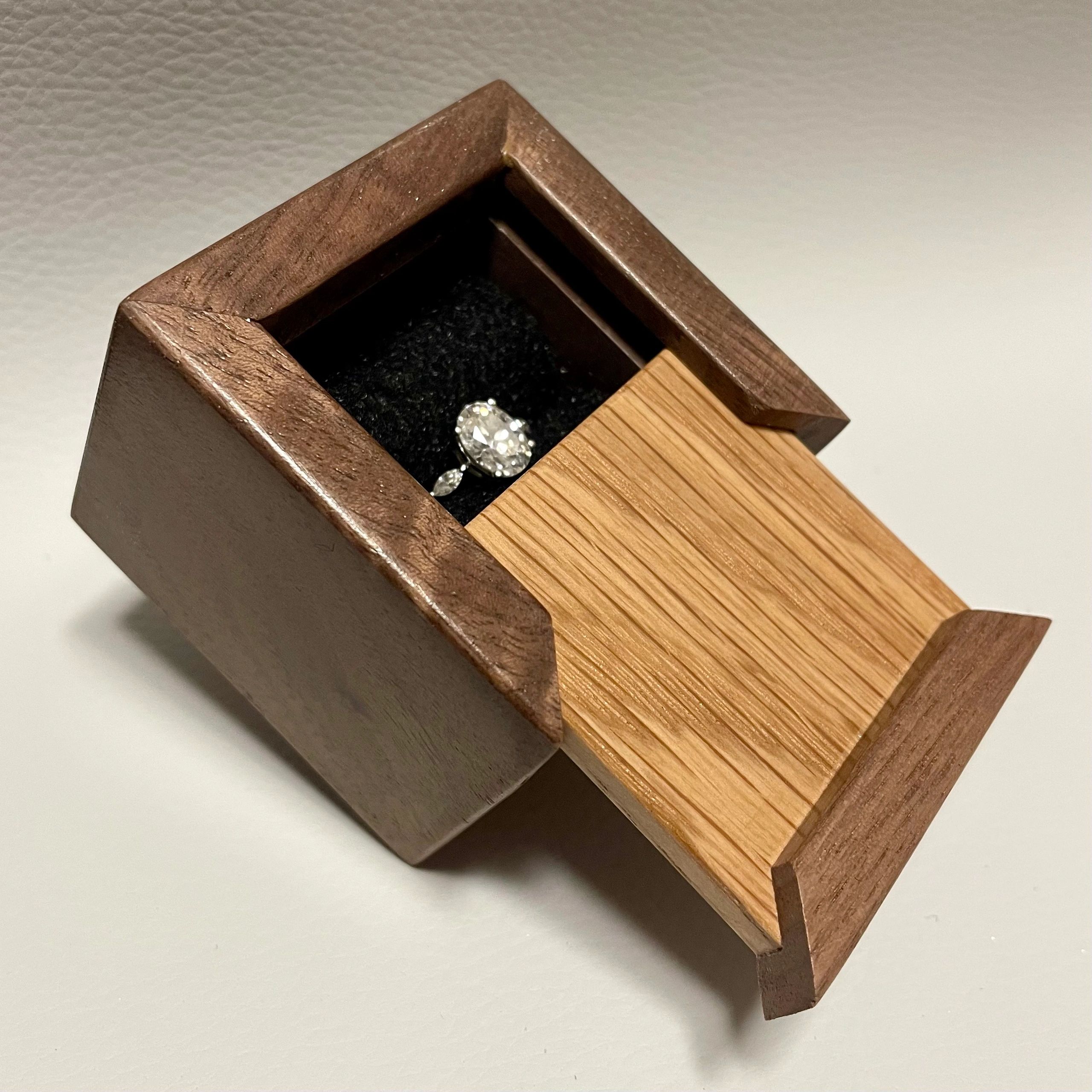 Wooden ring box with a diamond ring inside.