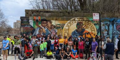 Group photo in front of a colorful mural on a city street.