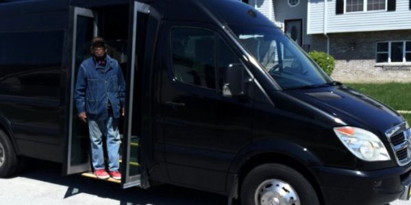 Man standing at the door of a black van.