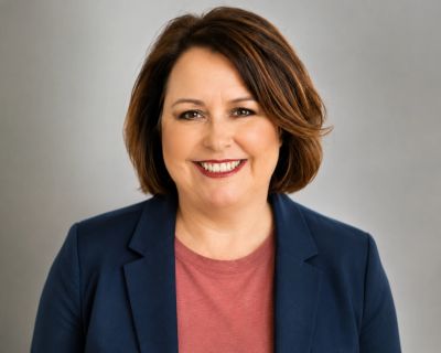 Professional woman with a warm smile wearing a navy blazer and red top.