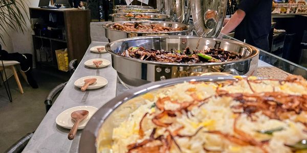 A buffet table with various dishes in large metal serving bowls.