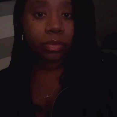 Close-up of a woman with braided hair in dim lighting.